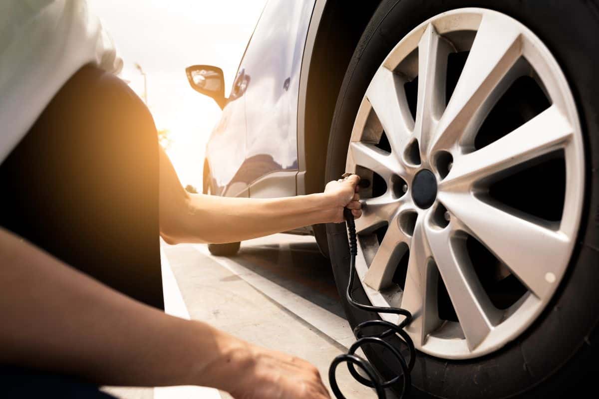 man measuring the tire pressure of a car