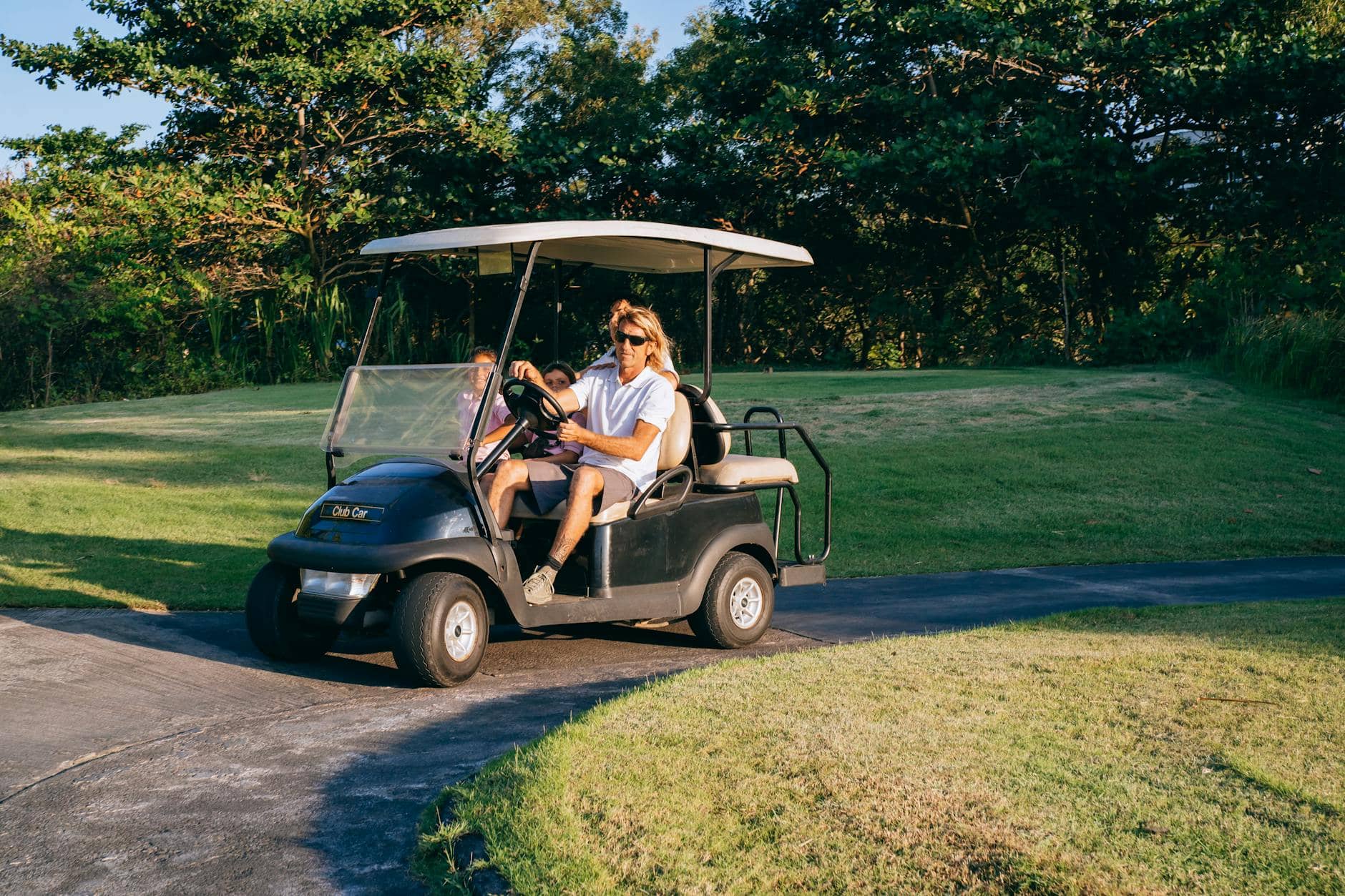 a man with kids riding on golf cart